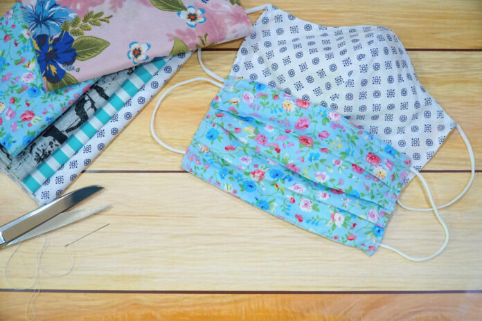 Stack of cotton, scissor, needle and DIY fabric mask on wood table. Protect dust, pollution (PM2.5), Virus, Bacteria. Handicraft concept. Copy space for any text design.