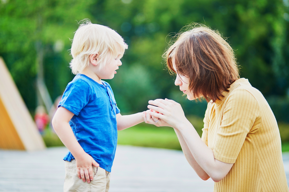 Madre che toglie una scheggia dalla mano del figlio piccolo.