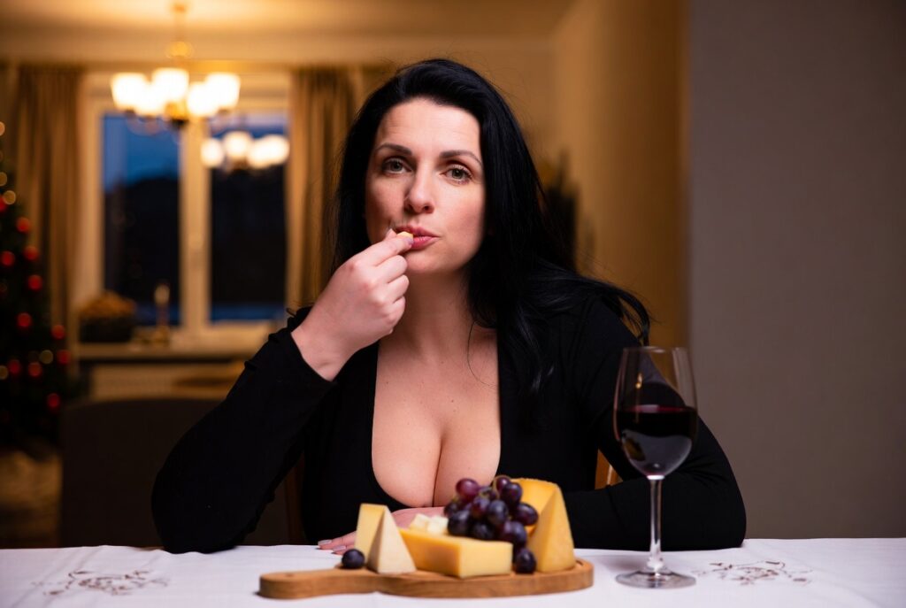 Donna che mangia il formaggio prima di bere il vino.