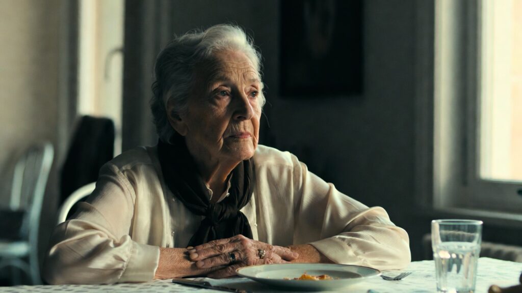 Donna anziana seduta a tavola con espressione pensierosa, simbolo della demenza nelle fasi iniziali