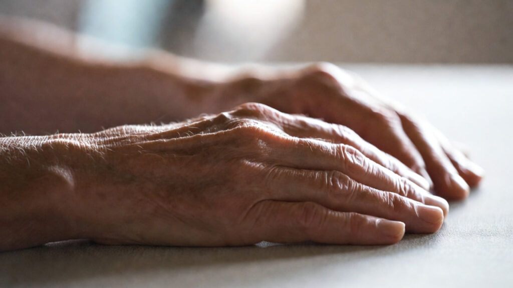 Mano anziana sul tavolo — segnali precoci del Parkinson, Giornata Mondiale 11 aprile 2026