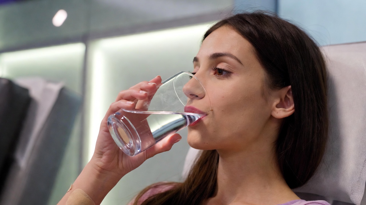 Giovane donna beve acqua e riposa dopo una donazione di sangue
